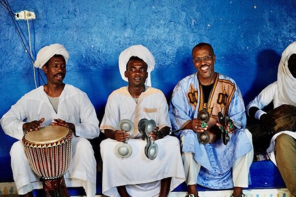 gnawa musicians performing in Khamlia Village with a blue background in the Sahara desert near Merzouga and Erg Chebbi
