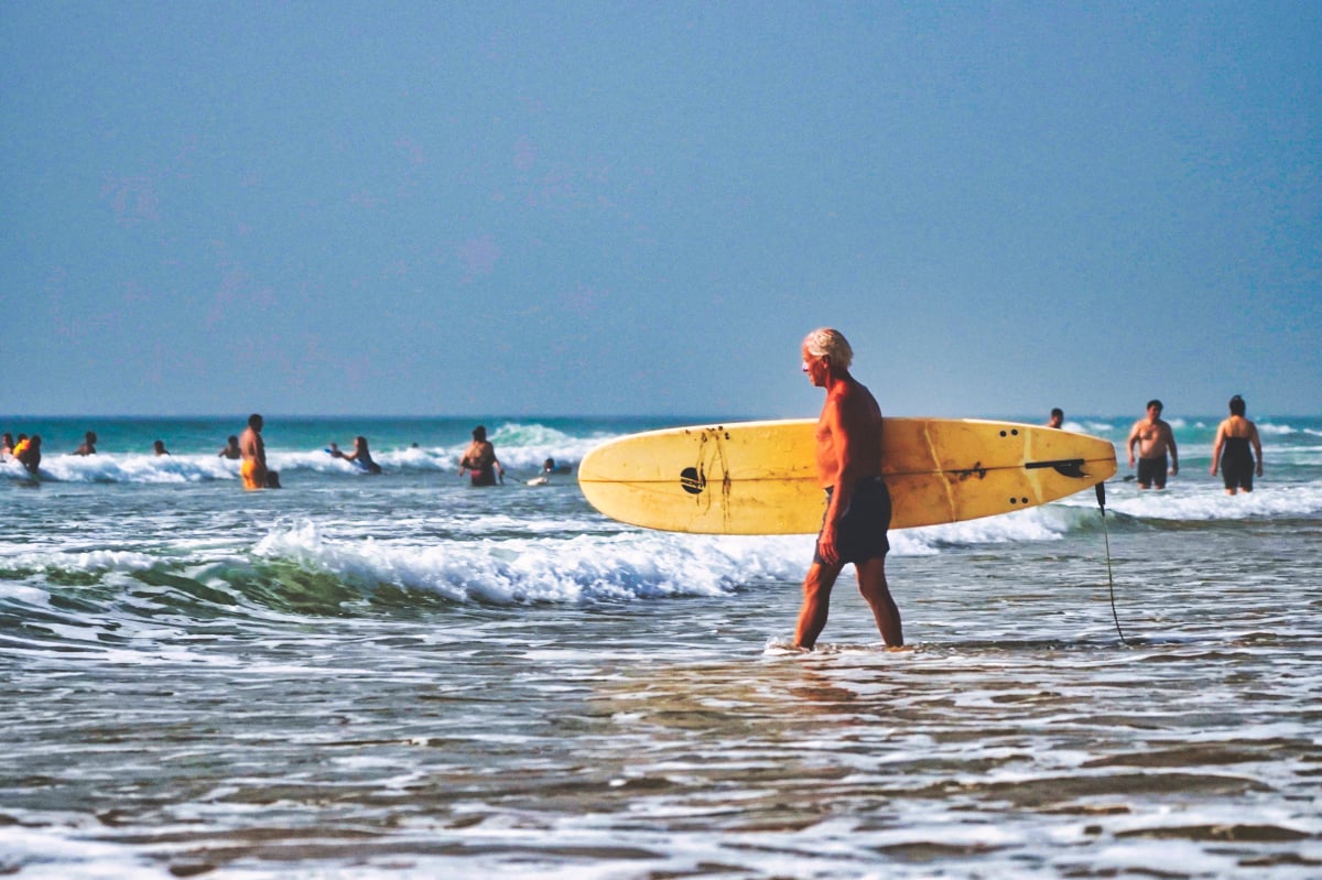 an older surfer heads out on the briech beach in north morocco near asilah and tangier at one of the most stunning beaches of asilah