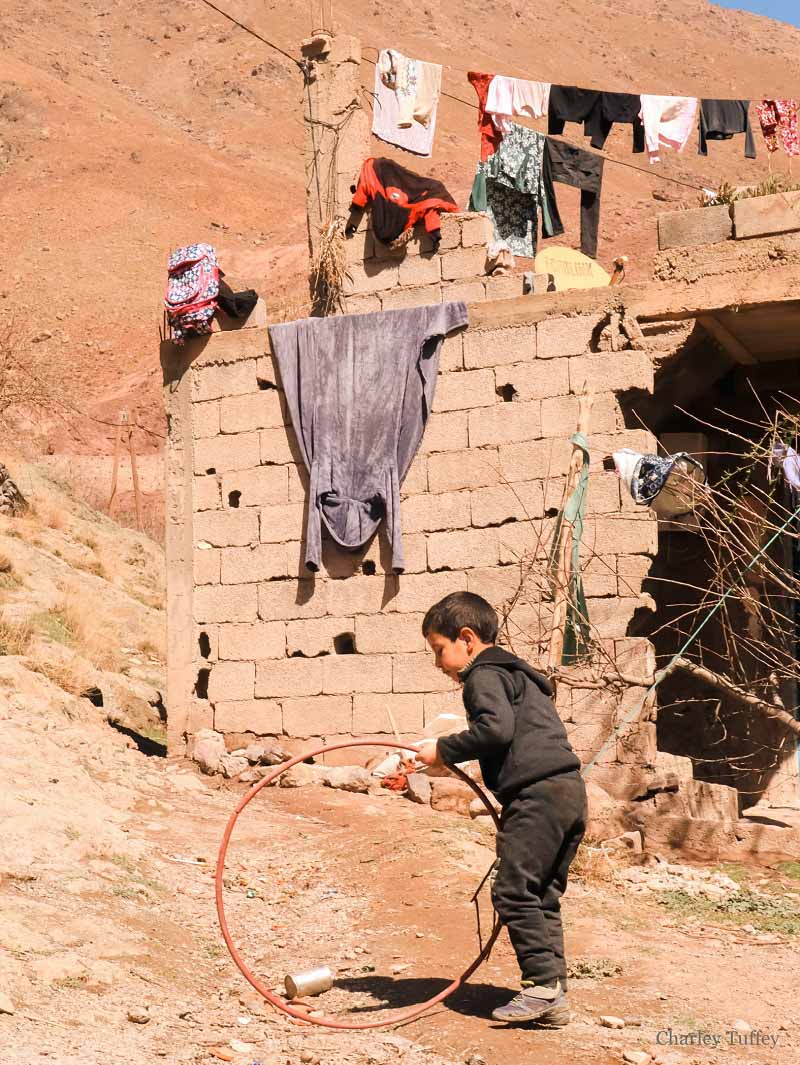 young moroccan berber boy playing with a hoop in a village in the atlas mountains photgraphed by charley tuffey
